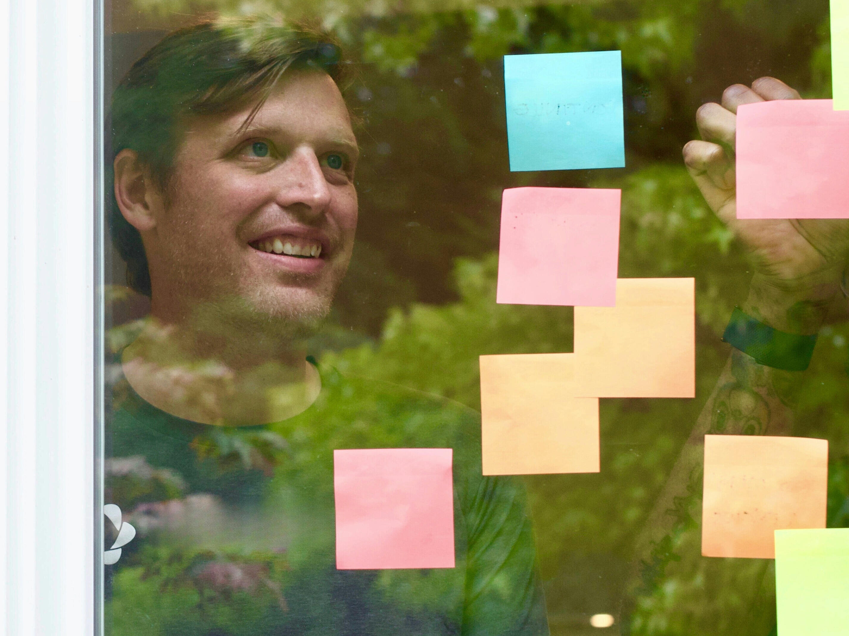 Mann klebt Post-its an ein Fenster