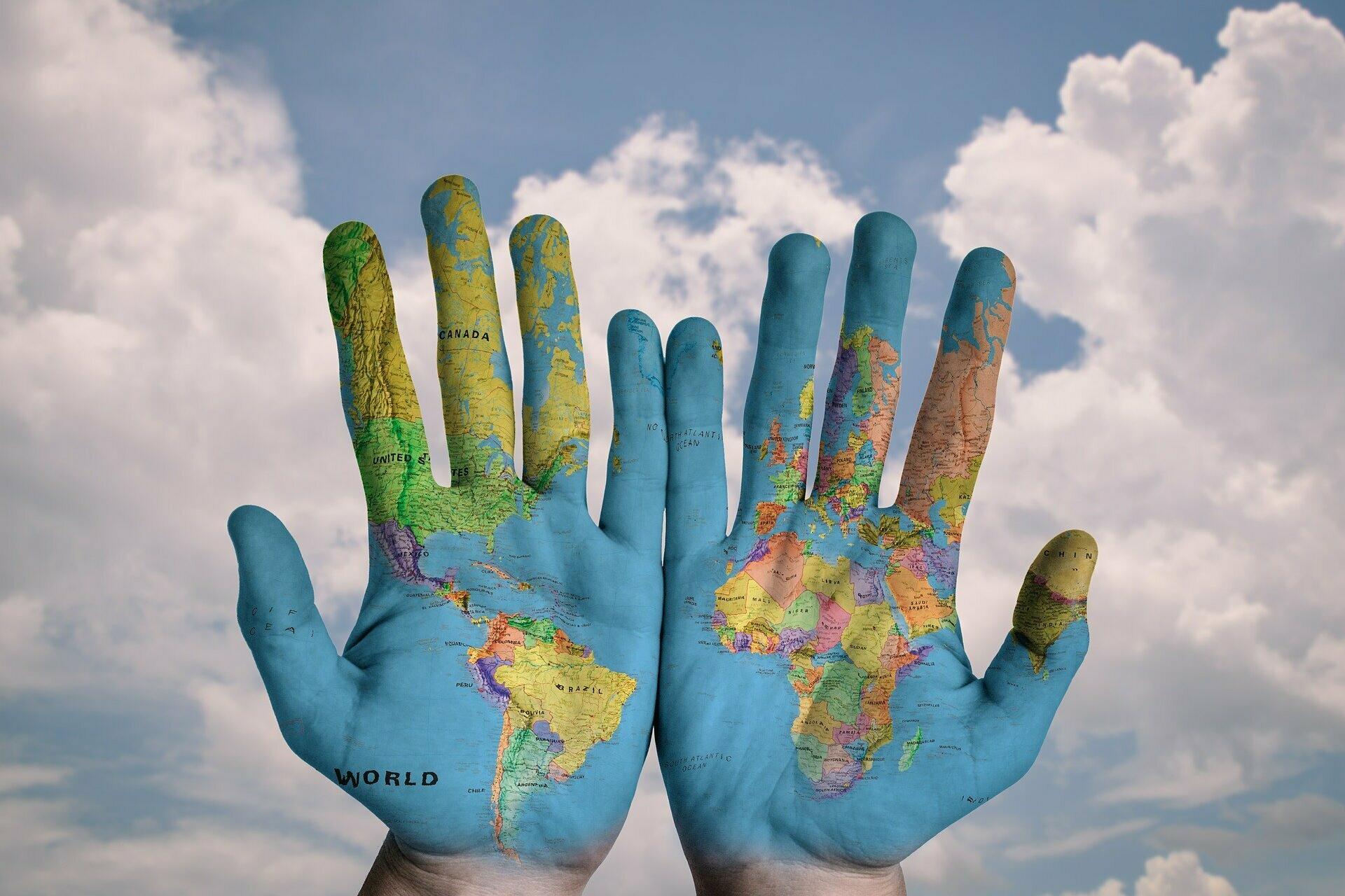 Zwei aufgeschlagene Hände mit aufgezeichneter Weltkarte.